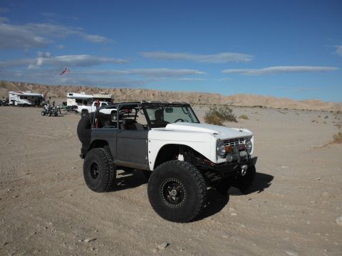 1979 Ford Bronco - A modified 1979 Ford Bronco is seen in a desert setting, with other vehicles and RVs present.