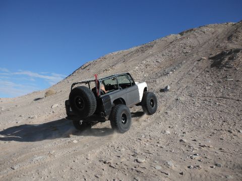 1979 Ford Bronco - Off-road vehicle navigates a challenging incline on a rocky, desert-like terrain.