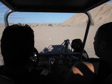 1979 Ford Bronco - Two people ride in a buggy through a desert landscape under a clear blue sky.