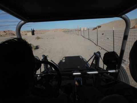 1979 Ford Bronco - Driving a dune buggy through a desert landscape, with a small building and fence visible in the distance.