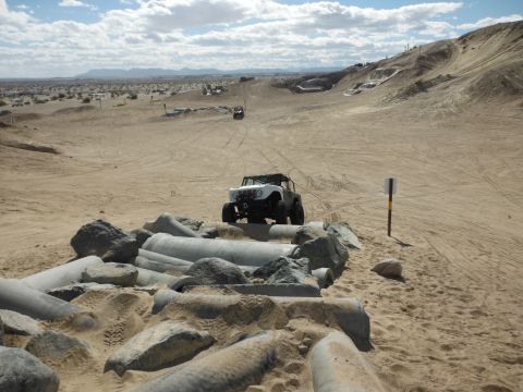 1979 Ford Bronco - Off-road vehicles navigate a desert landscape with sandy dunes and rocky obstacles.