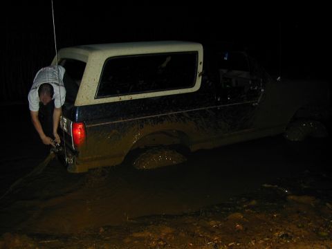 1996 Ford Bronco - Ford Bronco is stuck in mud, with a person attempting to pull it out.
