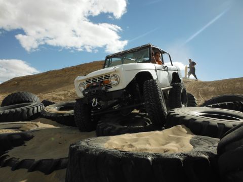 1979 Ford Bronco - This modified 1979 Ford Bronco tackles a challenging obstacle course made of tires in a desert landscape.