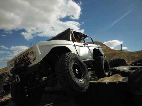 1979 Ford Bronco - This modified vehicle is navigating a challenging off-road course with a clear sky above.