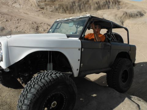1979 Ford Bronco - A modified 1979 Ford Bronco navigates a sandy terrain, its off-road capabilities with a lifted suspension and aggressive tires.