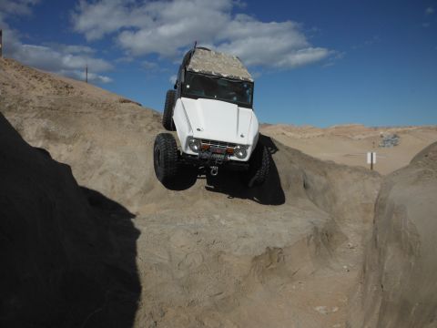 1979 Ford Bronco - White 1979 Ford Bronco navigates a steep, rocky trail under a blue sky.