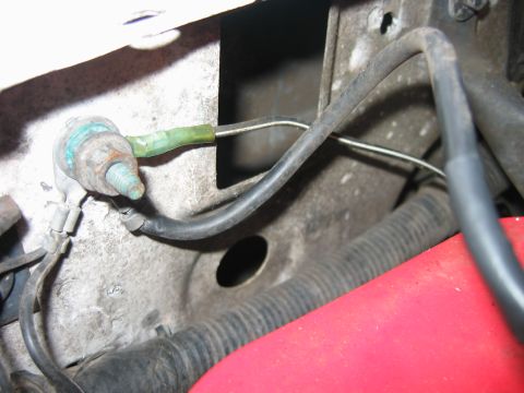 1992 Ford Bronco - Close-up view of a vehicle's ground wire connection, showing a corroded bolt and green insulated wire.