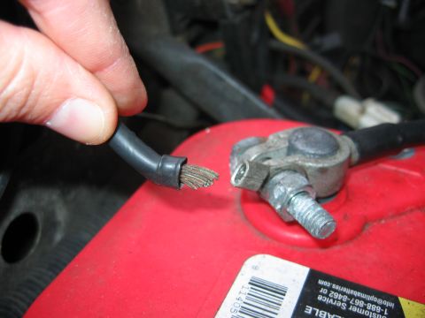 1992 Ford Bronco - A frayed battery cable is shown being held near its terminal on a red car battery.