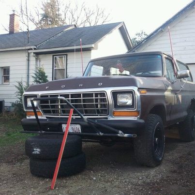 1979 Ford Bronco - This Ford Bronco is parked in front of a house with spare tires stacked beneath its front end.