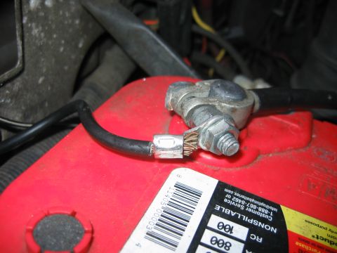 1992 Ford Bronco - A close-up shot focuses on a car battery terminal and its connected cable, with some text visible on a sticker.