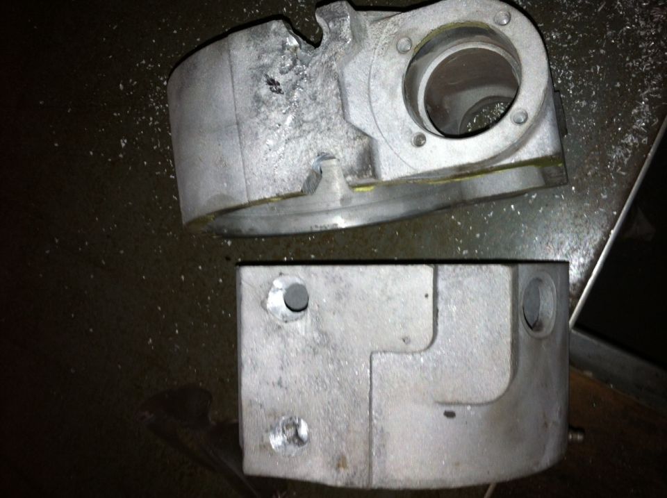 Two machined aluminum engine block sections with bolt holes and internal passages