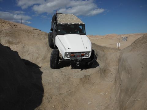 1979 Ford Bronco - Off-road vehicle navigating a challenging rocky terrain under a blue sky.