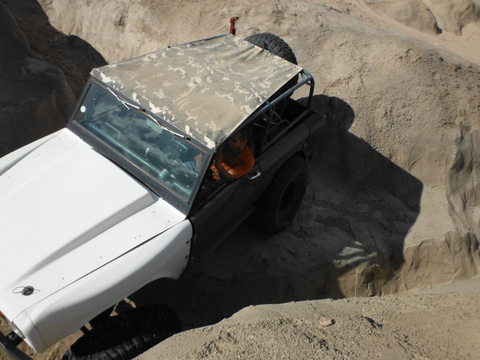 1979 Ford Bronco with camouflage soft top navigating sandy terrain