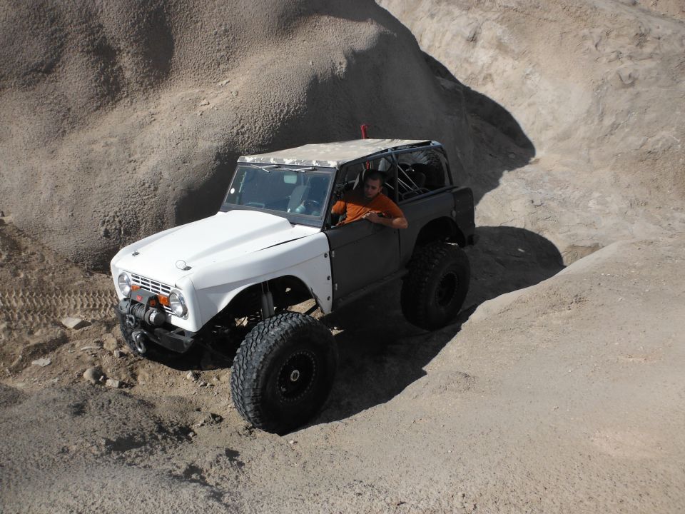 White and grey off-road vehicle with large tires driving on a dirt path