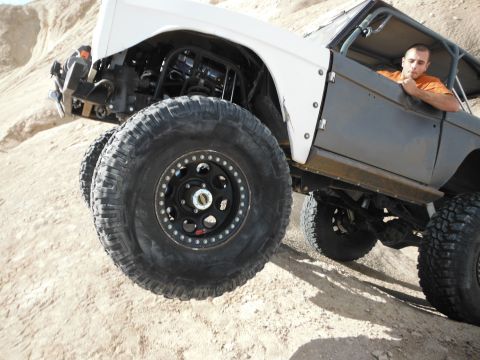 1979 Ford Bronco - A heavily modified SUV navigates a steep, sandy incline with a driver inside.