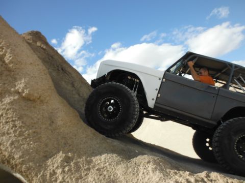 1979 Ford Bronco - A modified Ford Bronco navigates a steep, sandy incline under a partly cloudy sky.