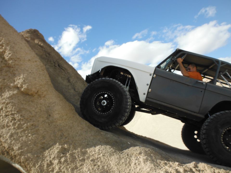 1979 Ford Bronco climbing a sandy hill with a driver inside
