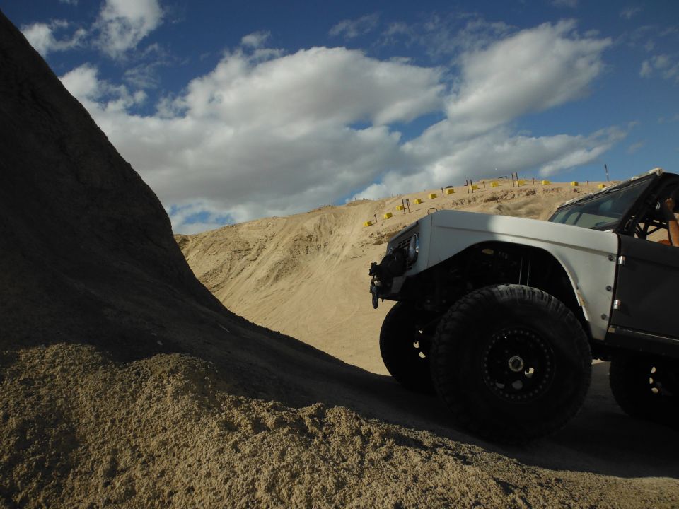 White off-road vehicle with large tires on a sandy incline