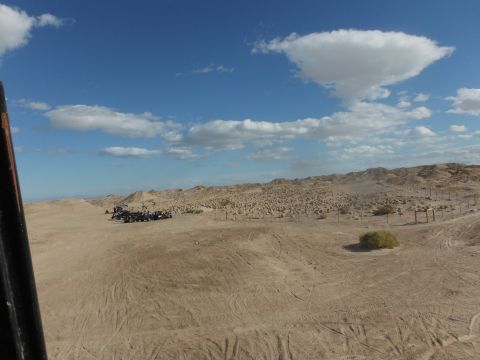 1979 Ford Bronco - A group of off-road vehicles are gathered in a dry, desert terrain under a partly cloudy sky.