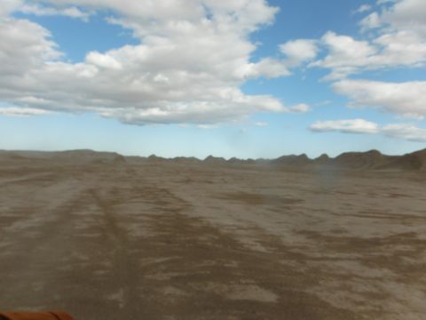 1979 Ford Bronco - Vast desert terrain with visible tire tracks under a partly cloudy sky, a Supermotors.net watermark.