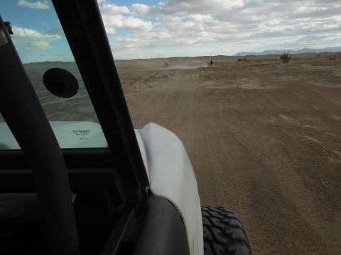 1979 Ford Bronco - View from inside an off-road vehicle as it travels across a dusty desert terrain under a cloudy sky.