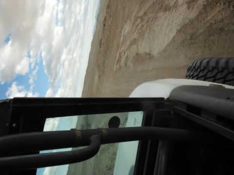 1979 Ford Bronco - Driving through a sandy desert terrain under a partly cloudy sky, with a view from inside the vehicle.
