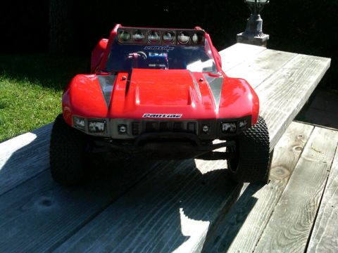 1986 Ford Bronco - A red remote control truck sits on a weathered wooden table outdoors.
