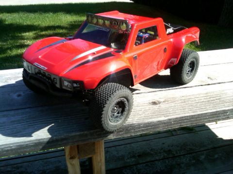 1986 Ford Bronco - This red RC off-road truck features a light bar on the roof and racing stripes on the hood.