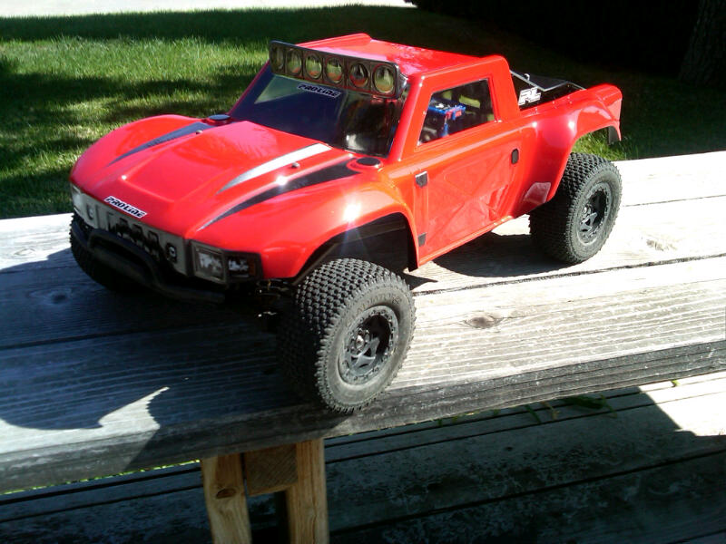 Red RC off-road truck with light bar and racing stripes
