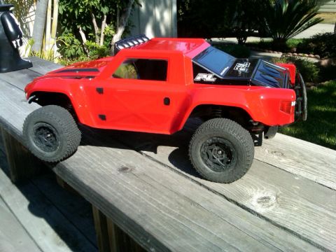 1986 Ford Bronco - A red RC truck sits on a wooden deck, with greenery in the background.