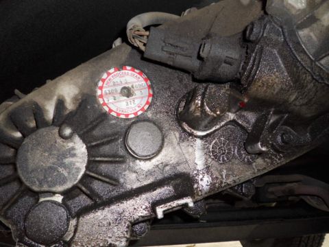 1994 Jeep Cherokee - Close-up of a greasy transfer case with a "New Process Gear" sticker, indicating it is a vehicle part.