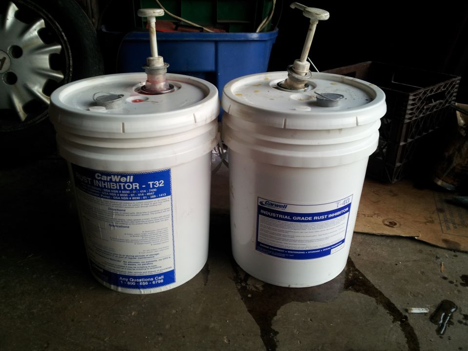 Two white 5-gallon buckets with pumps, one labeled CarWell Rust Inhibitor - T32