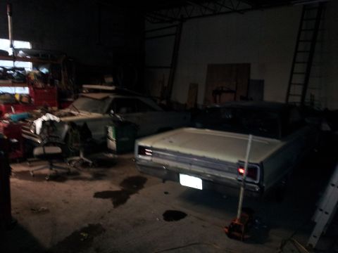 2006 Mitsubishi Evolution - Two classic cars are parked inside a dimly lit garage, with one car being worked on.