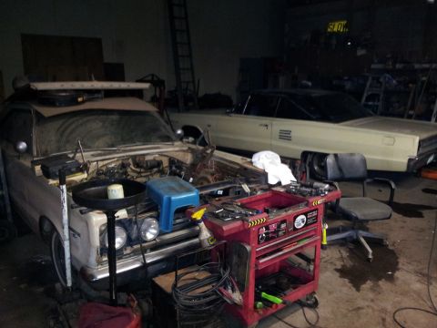 2006 Mitsubishi Evolution - Garage scene with two vintage cars undergoing maintenance, tools scattered around.