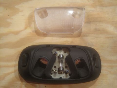1993 Ford Bronco - Overhead dome light assembly and its clear lens are shown separately on a wooden surface.