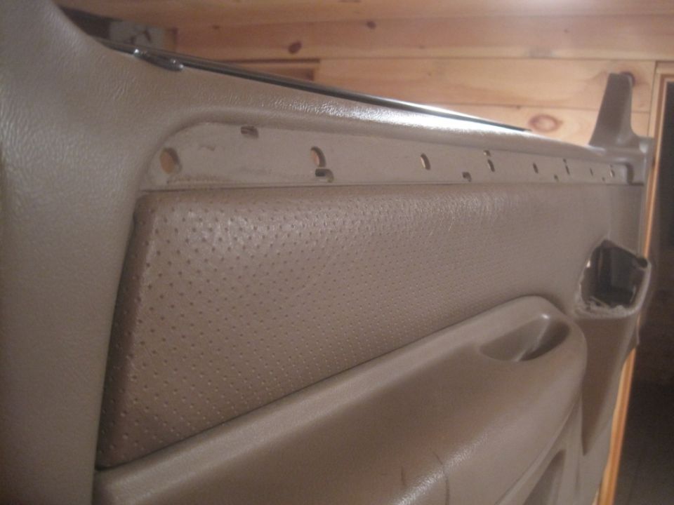 Tan perforated door panel with holes for trim pieces and a handle