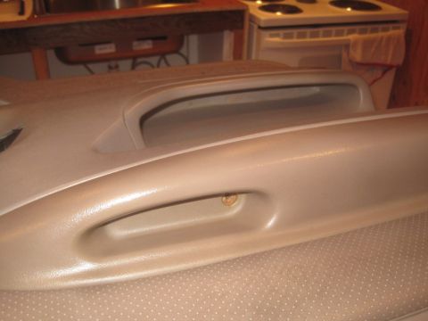 1993 Ford Bronco - Close-up of a tan interior car door panel, showing a grab handle and a visible screw.