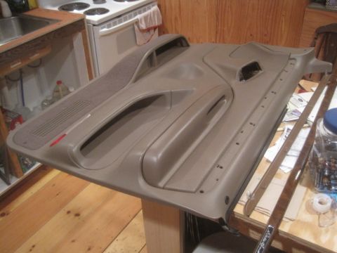 1993 Ford Bronco - A tan interior car door panel is displayed on a table, with a kitchen stove in the background.