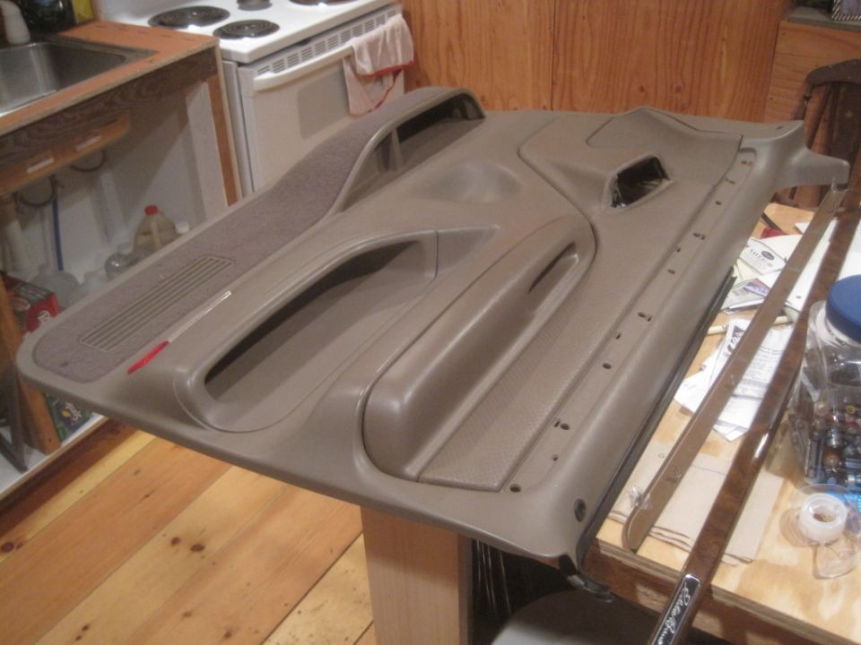 Car door panel with speaker grille and armrest, sitting on a wooden table