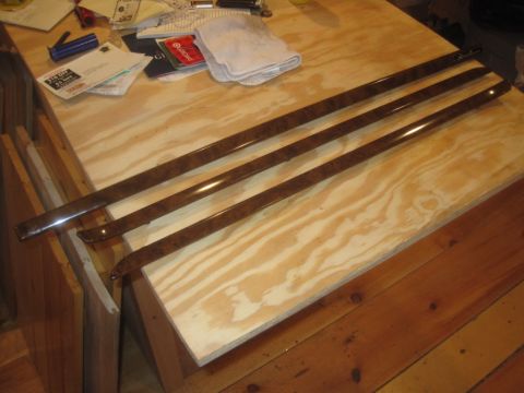 1993 Ford Bronco - Several wood grain trim pieces are displayed on a workbench, with various papers and a rag in the background.