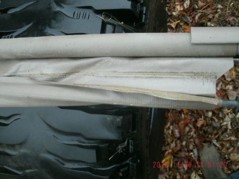 1994 Ford Bronco - Close-up of a light gray fabric-covered cargo cover or retractable tonneau/roll-up shade, torn open along its length to show the frayed edg…