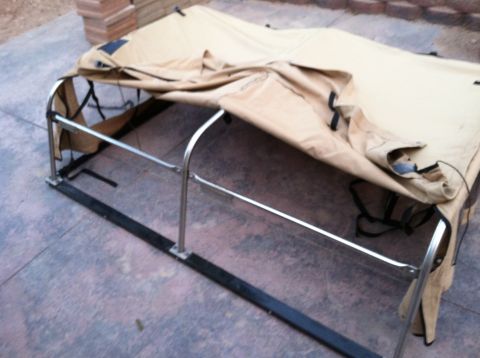 1985 Toyota Pickup/SR5 - A tan truck bed cover with a metal frame is shown from a side angle on a concrete surface.