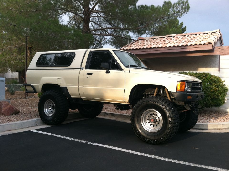 Cream 1985 Toyota Pickup/SR5 with camper shell and off-road tires, 3q-front view