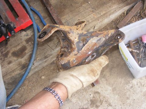 1996 Ford Bronco - A heavily rusted automotive part is examined, with tools and supplies visible nearby.