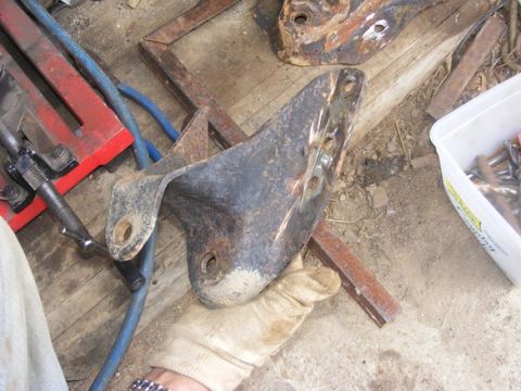 1996 Ford Bronco - Gloved hand holds a rusted metal bracket, with tools and other parts visible.