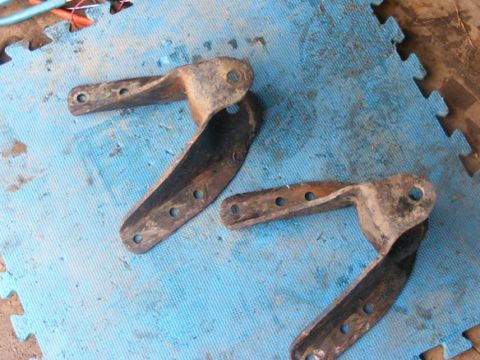 1996 Ford Bronco - These are two rusty metal brackets, likely suspension or mounting components, resting on a blue mat.