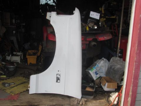 1996 Ford Bronco - A single white vehicle fender is the main subject, seen in a garage with other items.