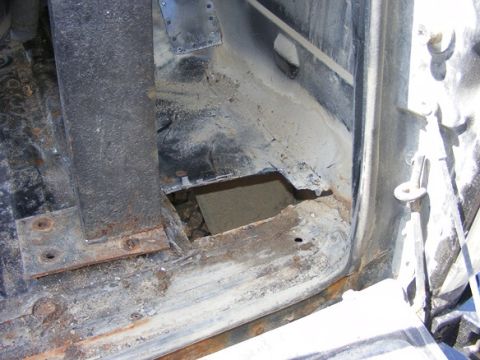 1996 Ford Bronco - The interior floor of a vehicle shows significant rust and damage, with a large hole exposing the area below.