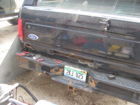 1996 Ford Bronco - Tools are laid out on the rusty rear bumper of a black Ford truck, ready for repairs.