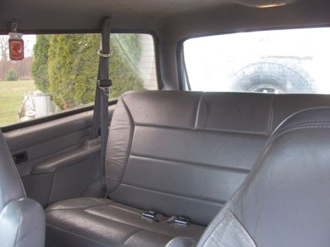 1996 Ford Bronco - Rear interior view of a 1996 Ford Bronco, with leather seats and a spare tire mounted at the back.
